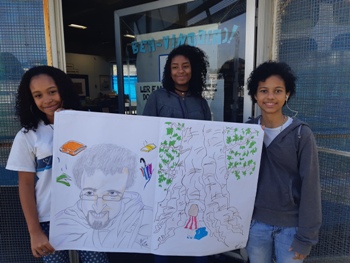A aluna Pâmela Thaynara (no meio) fez esta ilustração em homenagem ao escritor Lucinei M. Campos, com a ajuda de Aline Marques (de cabelo curto) e Rayane Araújo na pintura (Foto: Arquivo pessoal da professora) 